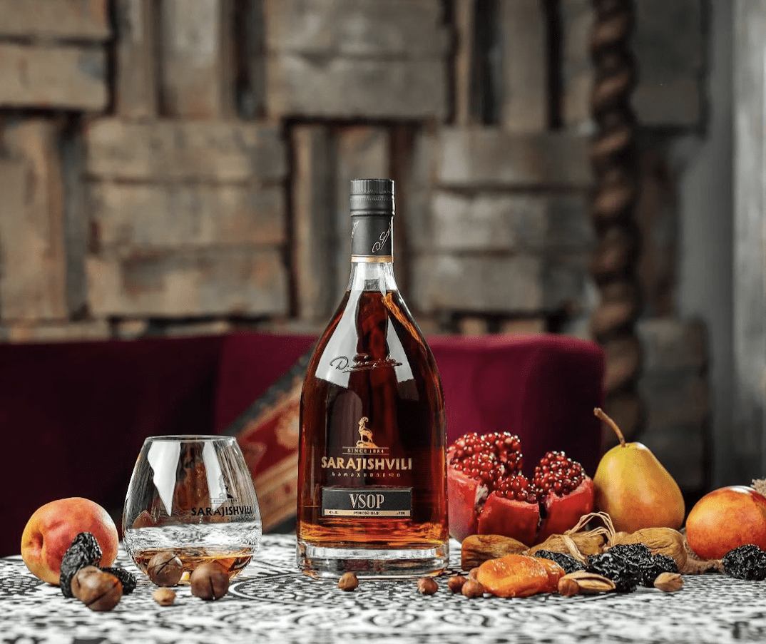 Gruzínský koňak Sarajishvili VSOP na stole s ovocem a ořechy, tradiční produkty z Gruzie
